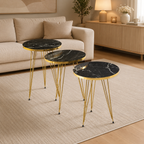 Three round side tables with black marble tops and gold metal legs in a living room setting.