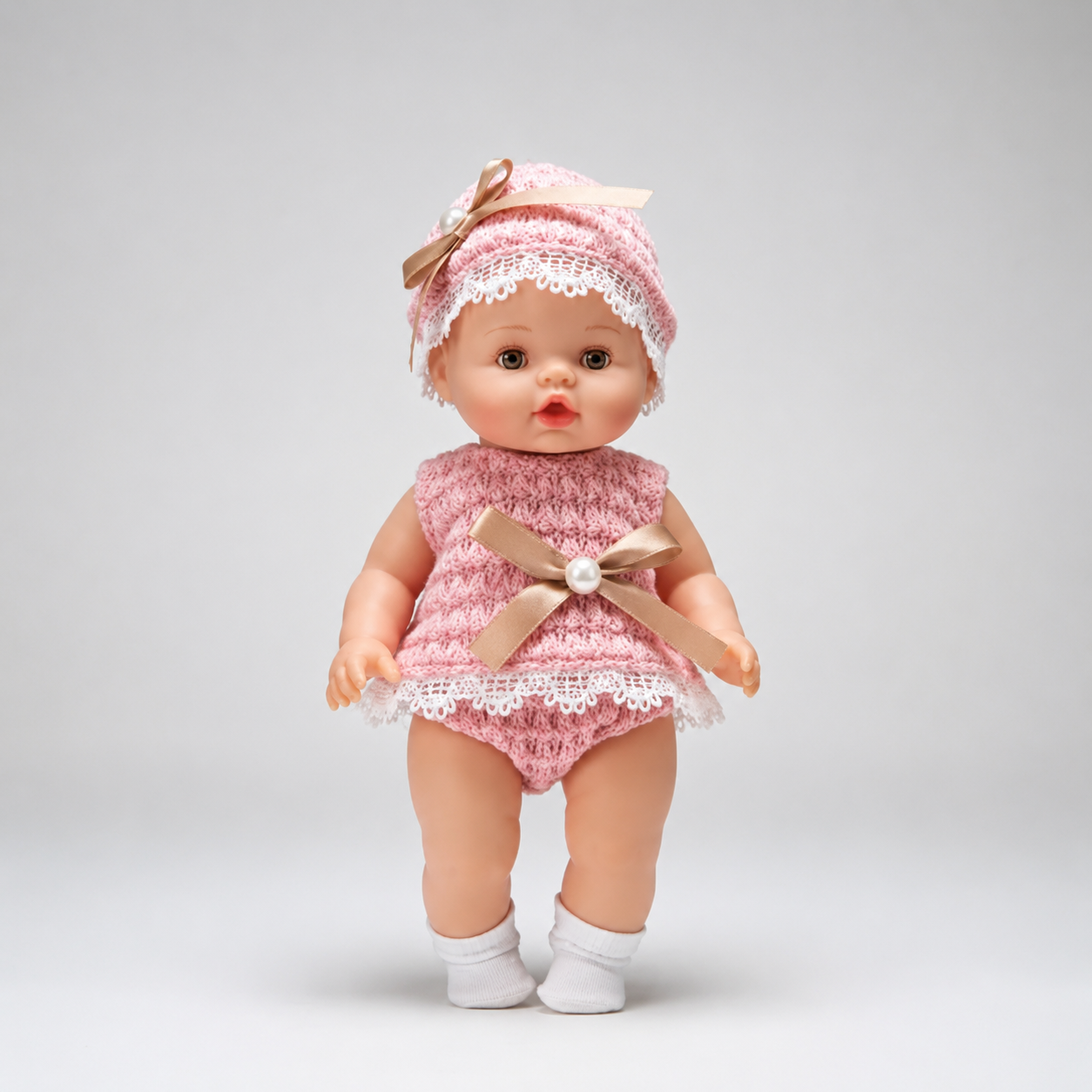 Baby doll in a pink outfit with a bow on a gray background