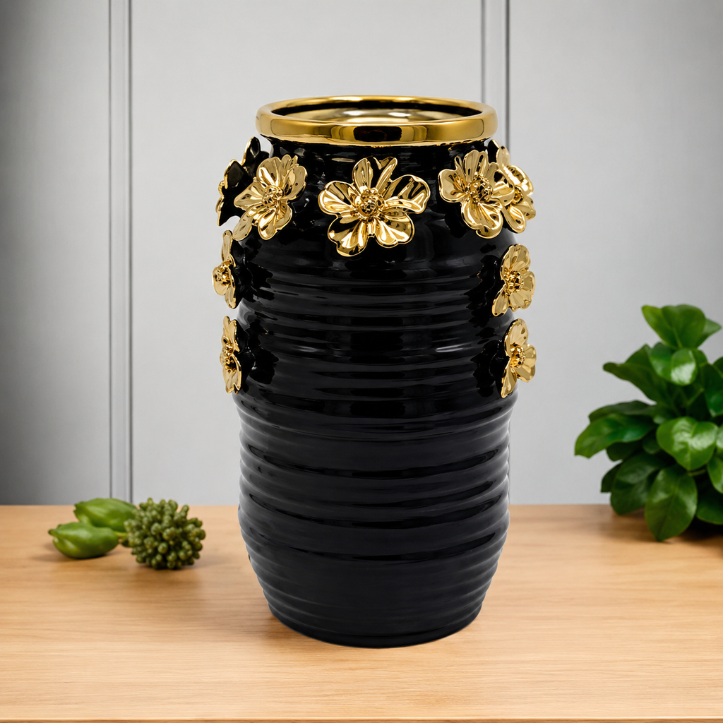 Black ribbed ceramic vase with gold flowers styled on wooden table with greenery