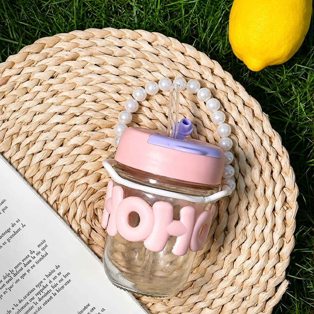 Glass jar with pink lid and 'HOHO' text on a woven mat with grass and lemon in the background