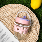 Glass jar with pink lid and 'HOHO' text on a woven mat with grass and lemon in the background