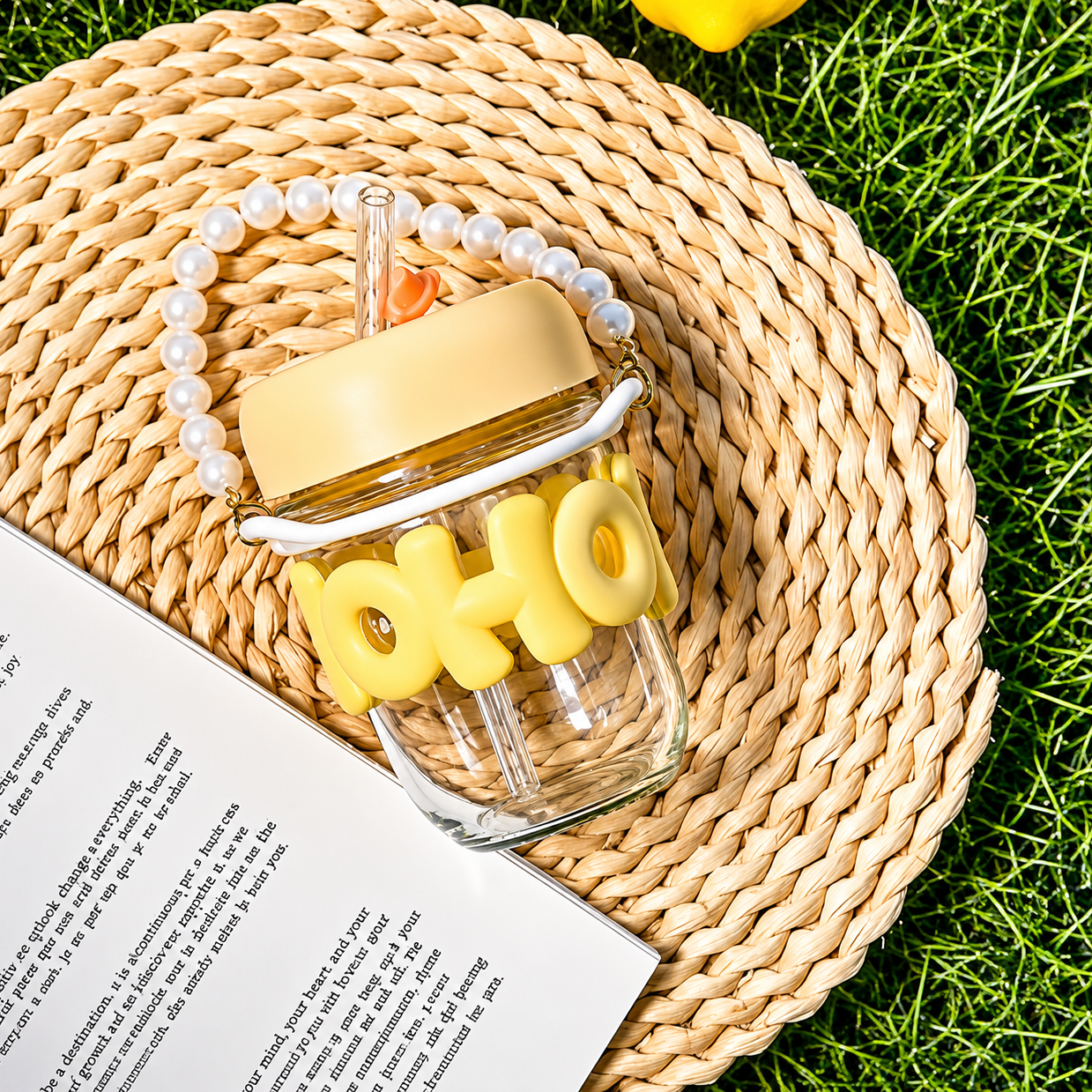 Glass jar with yellow text and accessories on a woven mat with grass in the background