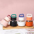 Set of four colorful glass bottles with handles on a wooden stand against a pink background.