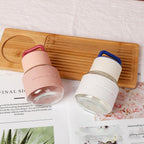 Two glass containers with silicone lids on a wooden board with a magazine underneath.