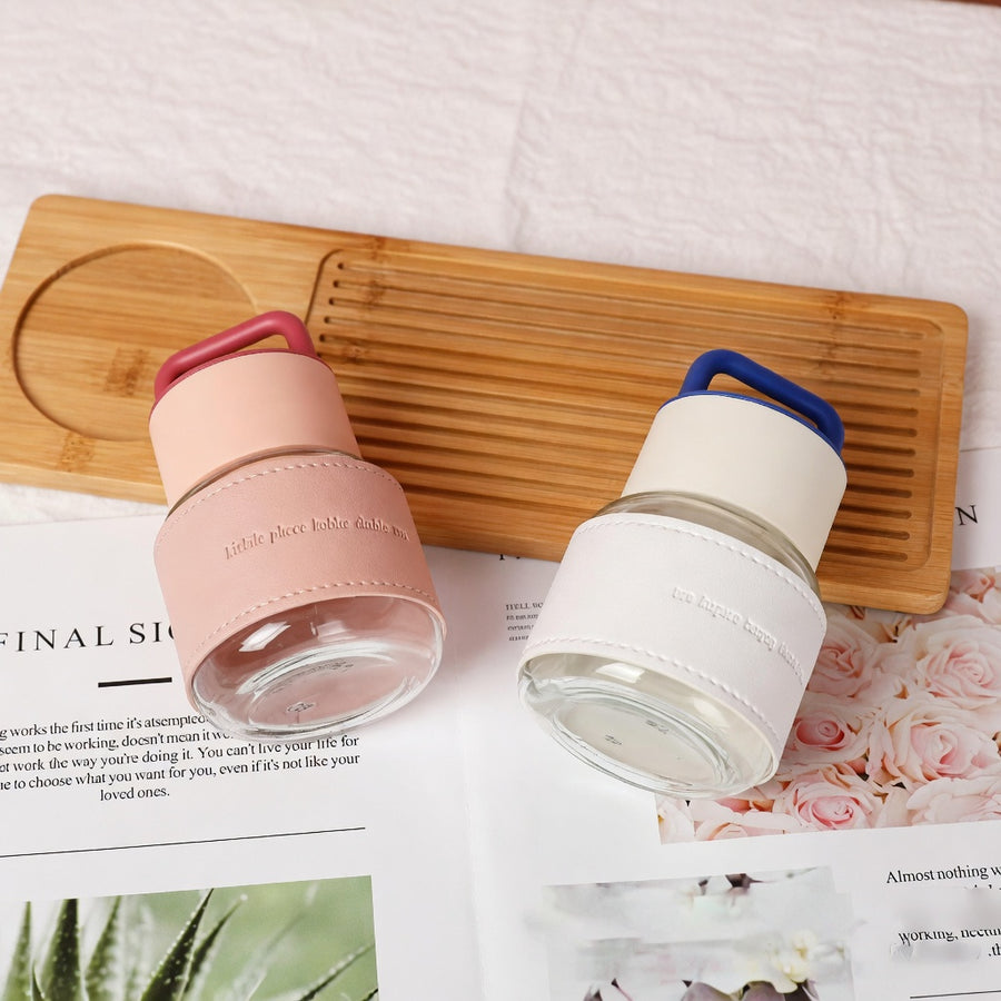 Two glass containers with silicone lids on a wooden board with a magazine underneath.