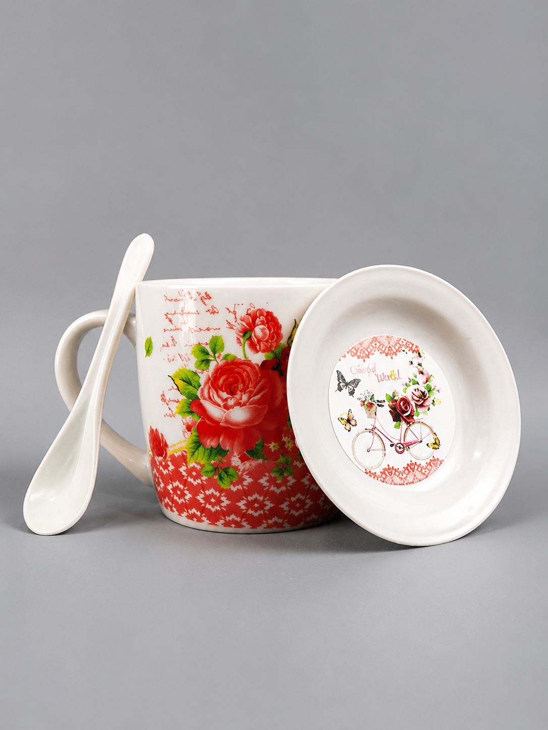 Decorative mug with floral design, spoon, and matching lid on a gray background