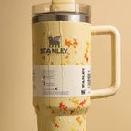 Stanley Quencher H2.0 tumbler in autumn leaf print with water dripping, dark background