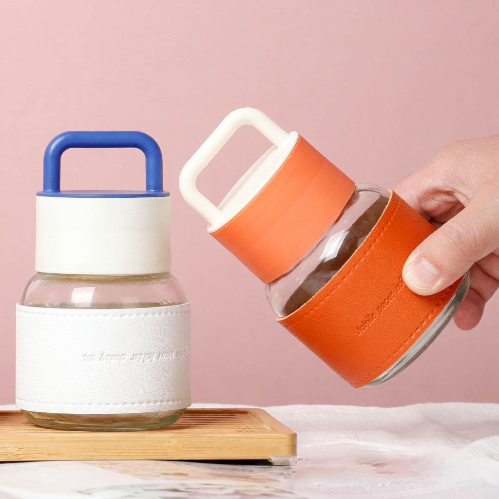 Two glass jars with colorful lids being held against a pink background