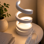White spiral LED lamp glowing warm light on bedside table with plant and books