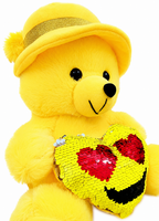 Yellow teddy bear with a sequined heart and yellow hat on a white background